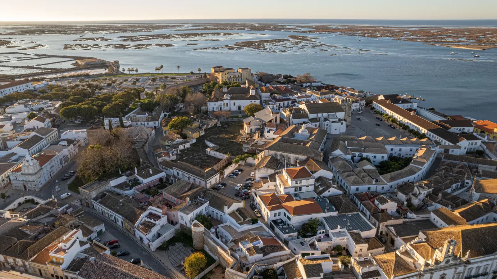 Aerial view of Faro's old town, white houses and tiled roofs, with the Ria Formosa lagoon and its islands behind