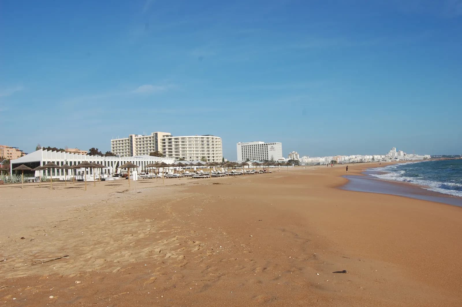 The wide sandy Praia da Marina at Vilamoura, with beach buildings and tall hotels along the shore
