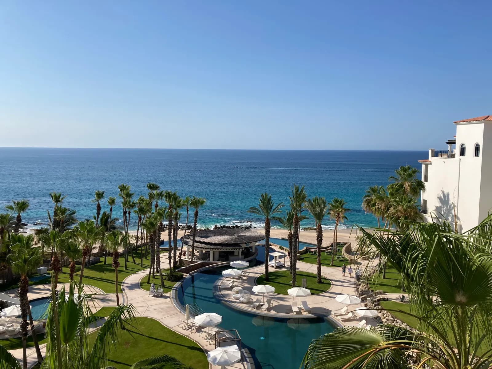 A resort on the Tourist Corridor seen from above, with pools, palm gardens and sun umbrellas running down to the beach and the Sea of Cortez