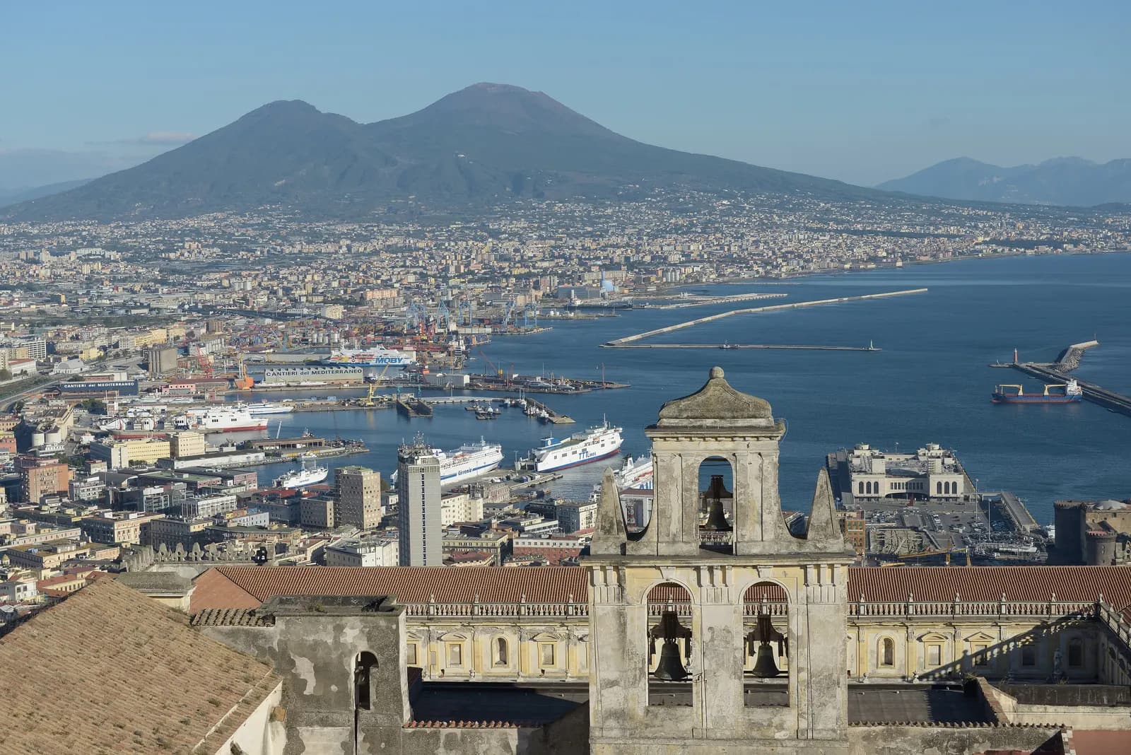 The bay of Naples and Vesuvius seen from Castel Sant'Elmo, with the port, its ferries and the bell tower of the Certosa di San Martino below.