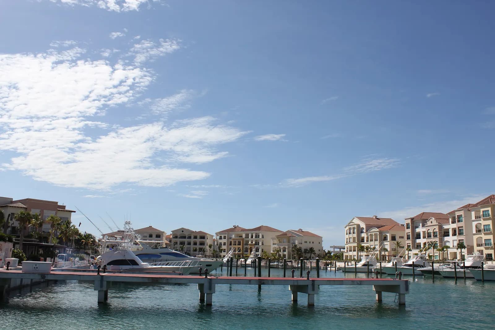 Yachts moored at the marina in Cap Cana, in front of cream-coloured town houses with red tiled roofs