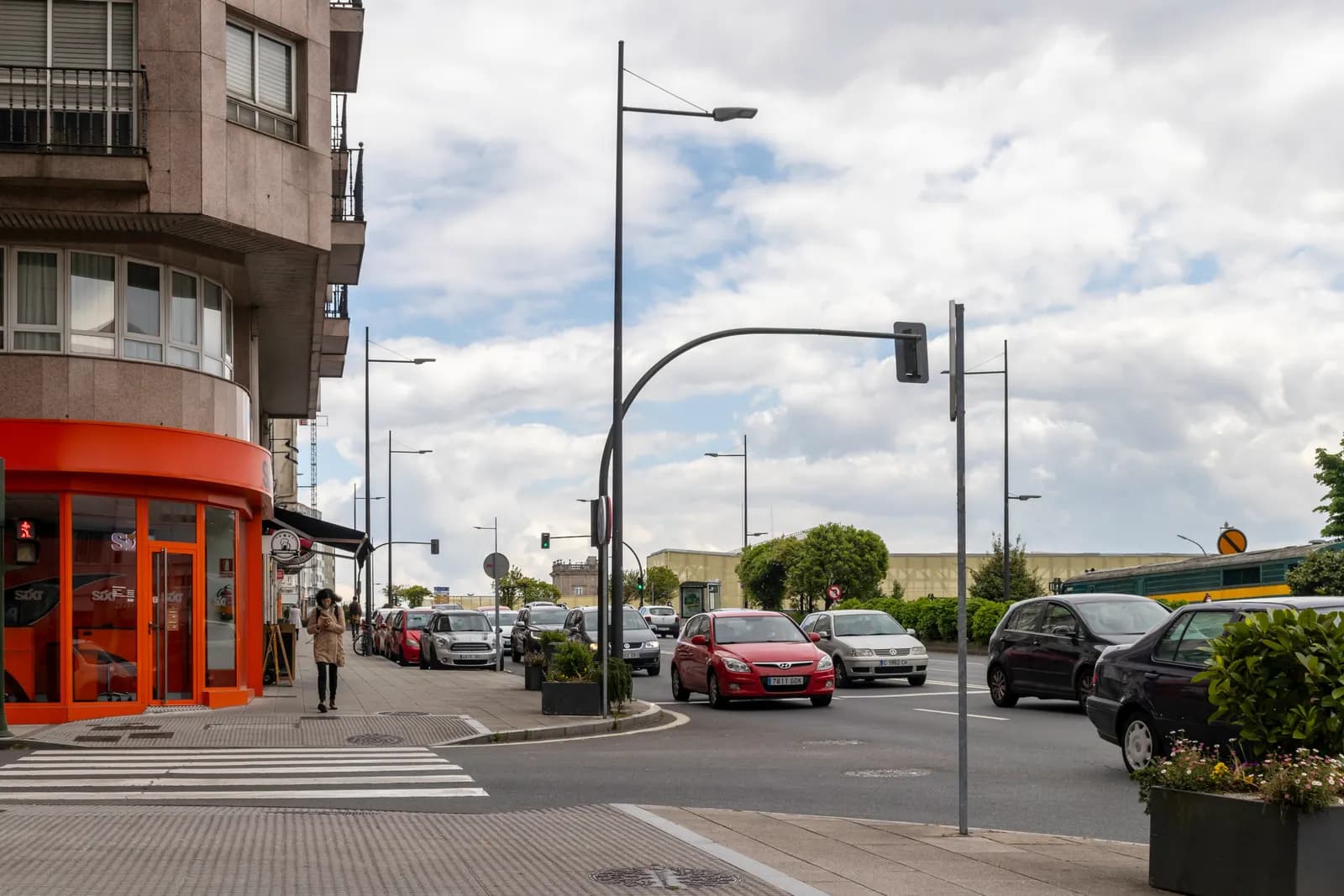 Rúa do Hórreo in Santiago's Ensanche, a street of shops and apartment blocks with cars at a crossing and traffic lights.
