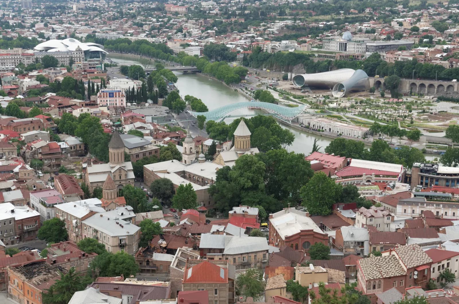 Old Tbilisi seen from Narikala, with red and tin roofs, a church, the Kura River, the Peace Bridge and the Rike park beyond