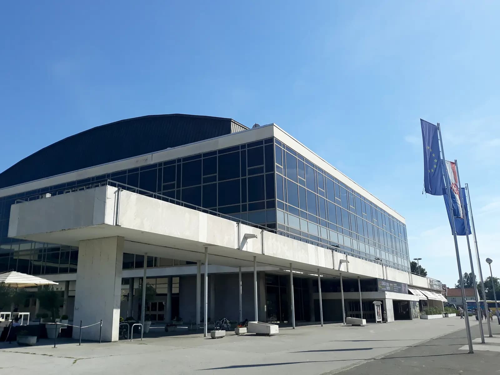 The Vatroslav Lisinski concert hall in Zagreb's Trnje district, a modernist glass and concrete building with flags outside