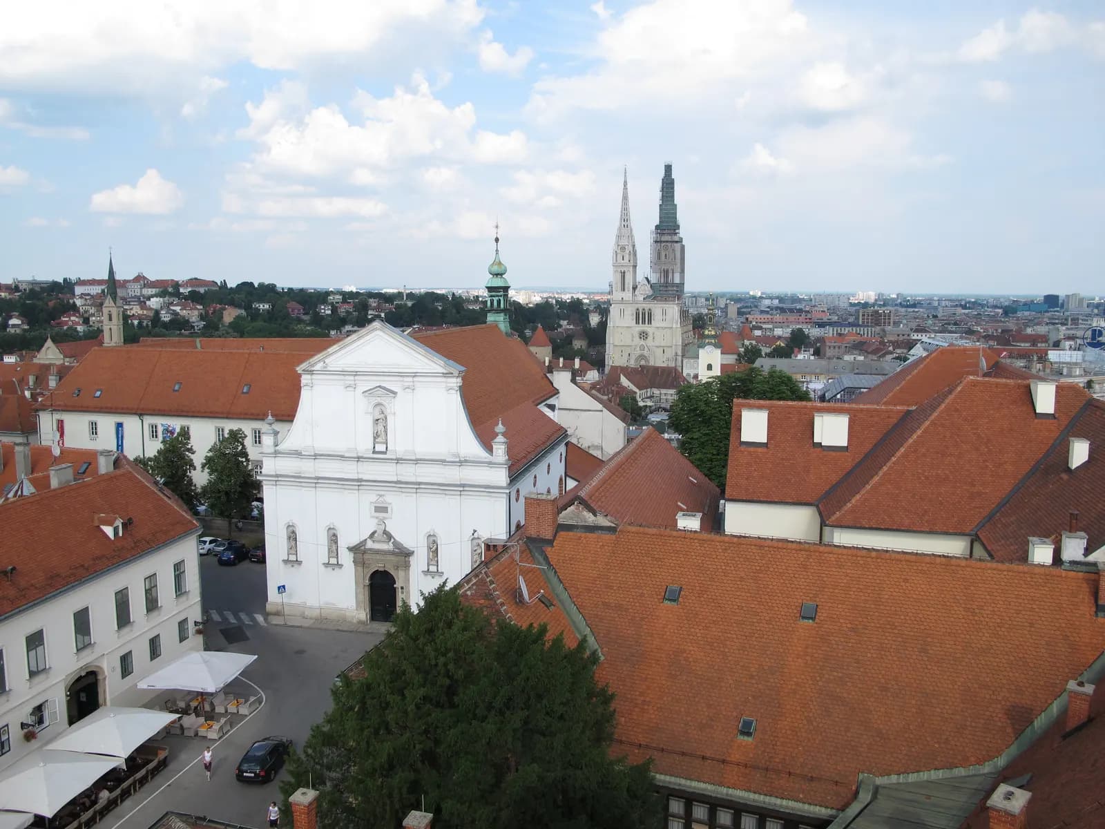 Red roofs of Zagreb's Upper Town seen from the Lotrščak tower, with the white facade of St Catherine's church and the cathedral towers behind
