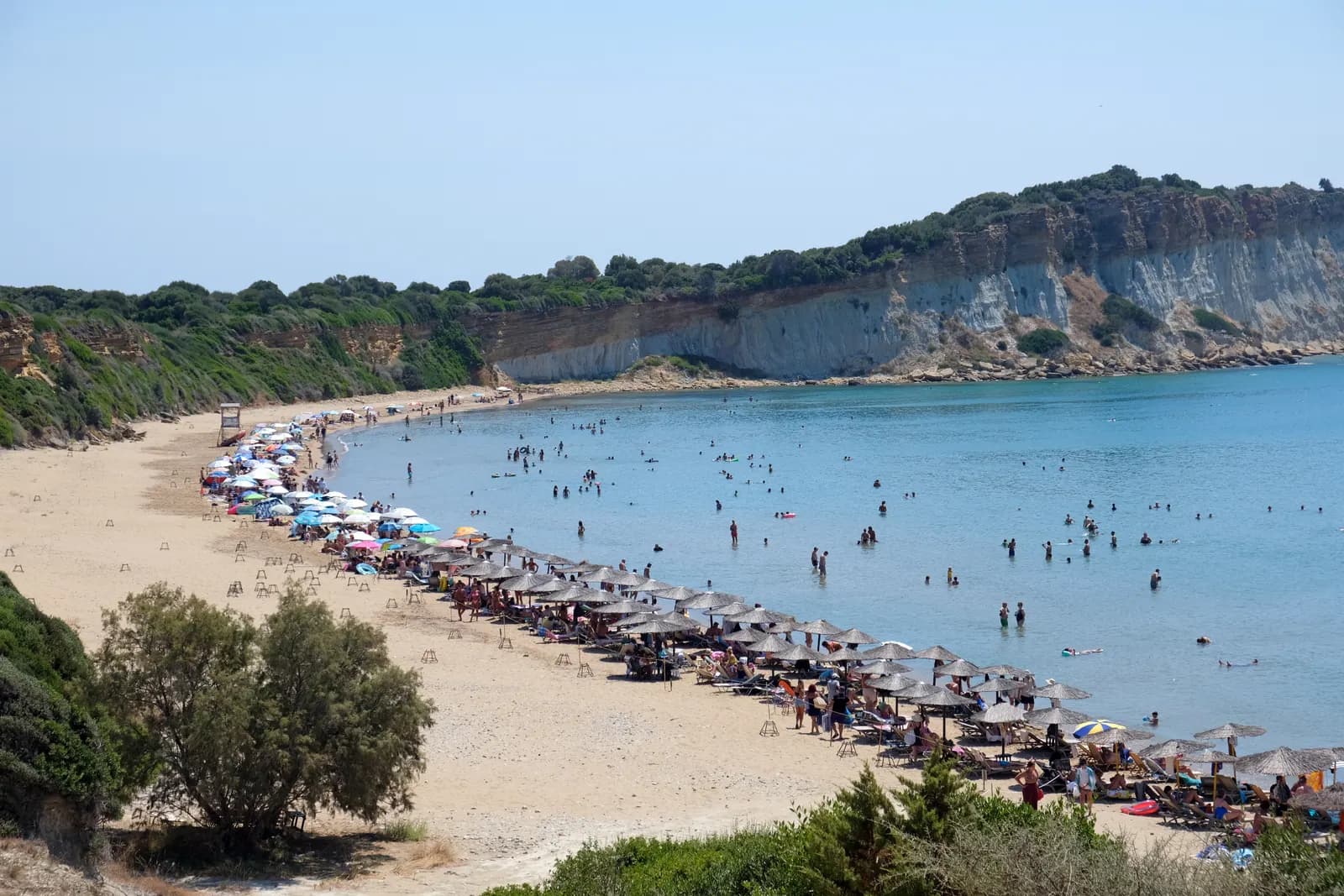 Gerakas beach at the tip of the Vasilikos peninsula, a curve of pale sand below eroded clay cliffs and clear shallow water