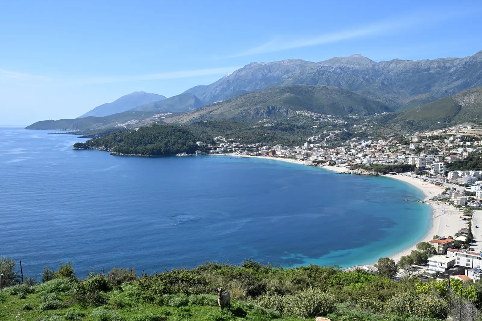 The bay of Himarë seen from the hills to the south: a long pale beach, the town along the shore and the mountains of the Albanian Riviera behind