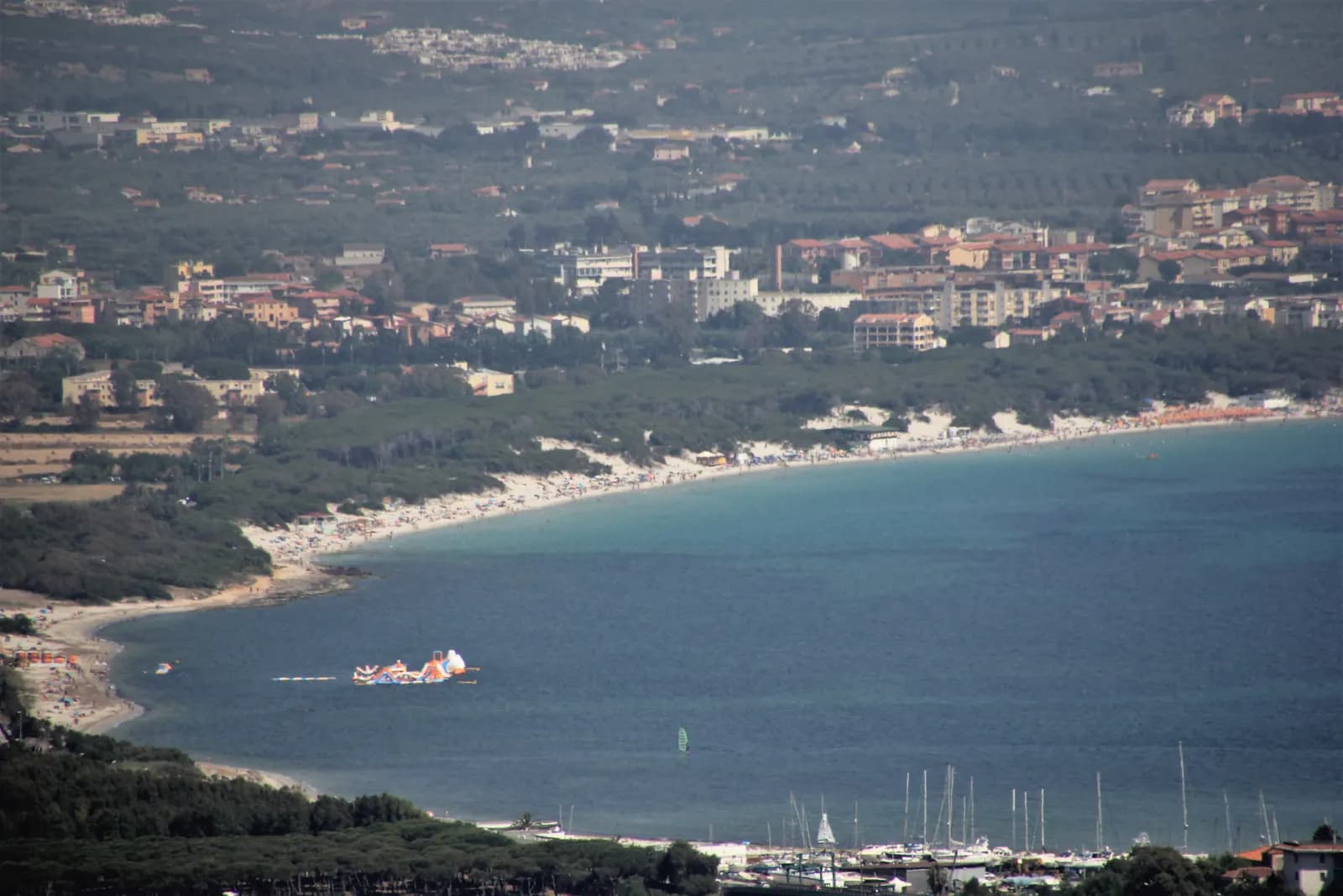 The bay of Maria Pia at Alghero from above, a long sandy beach backed by pine woods with the town behind