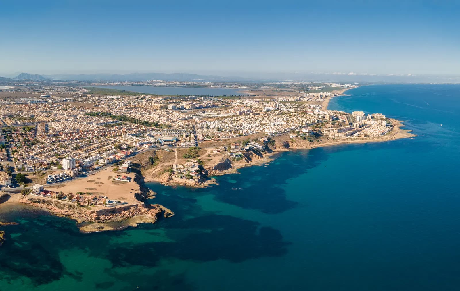 Aerial view of the rocky coast of Torrevieja, with the town, its beaches and a lagoon inland.