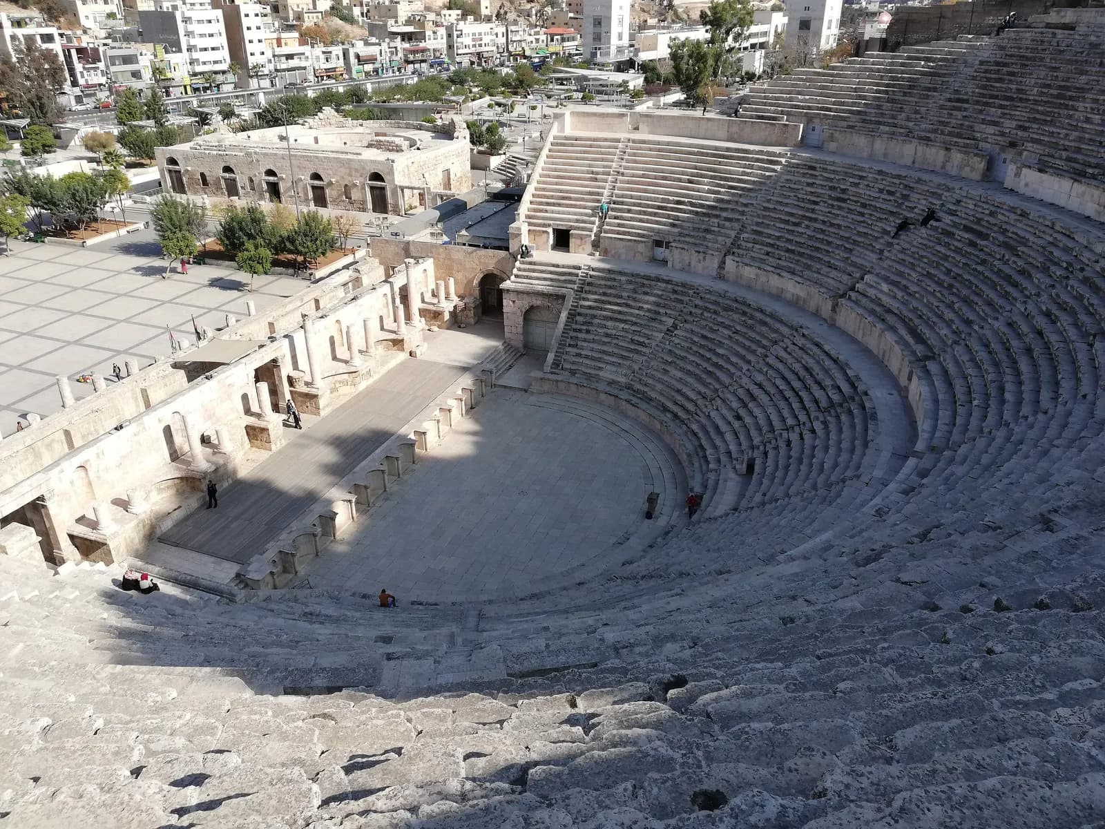 The stone tiers and stage of the Roman theatre in Downtown Amman seen from the upper seats, with the Odeon and the Hashemite Plaza beyond