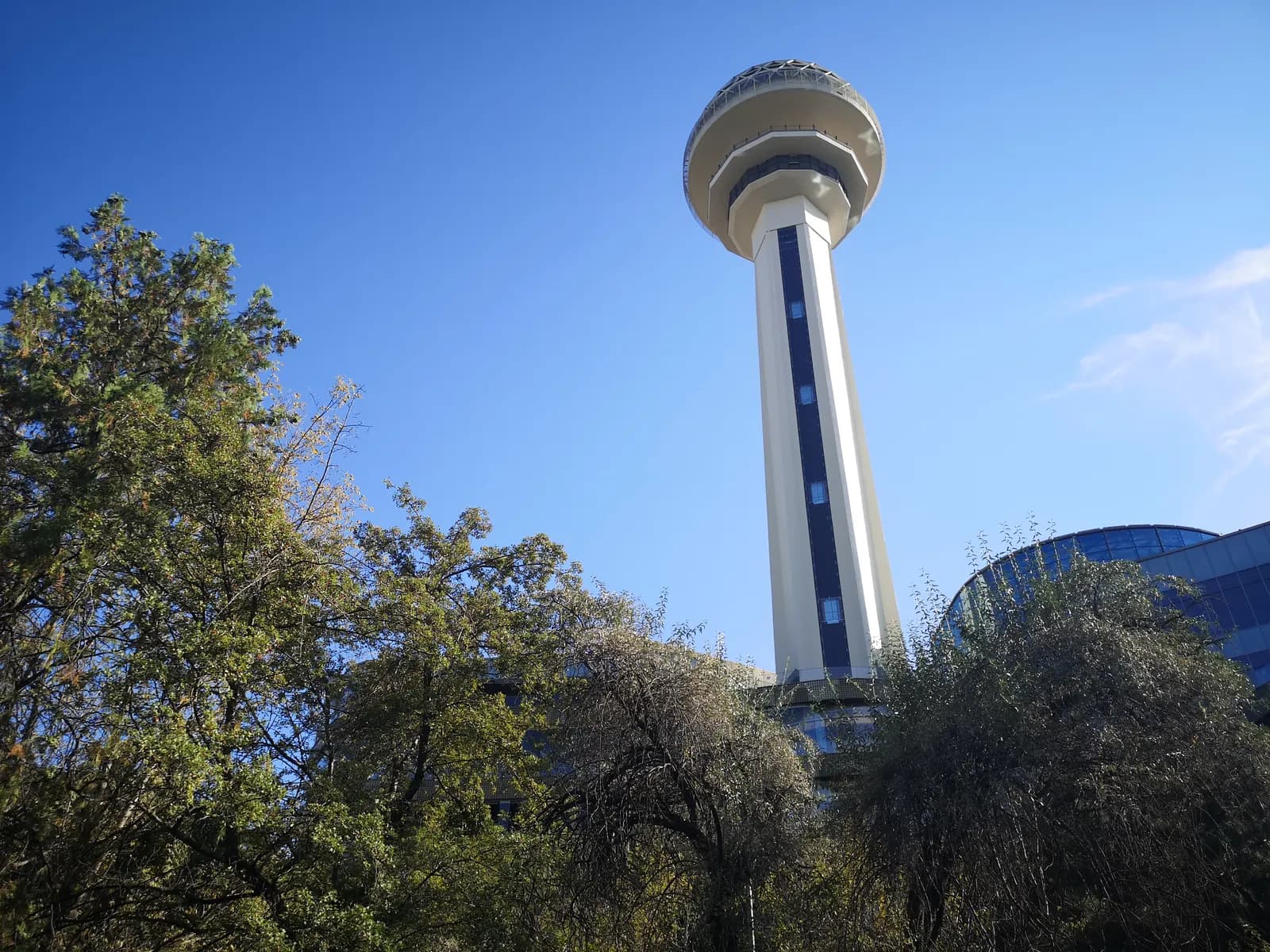 The Atakule tower in Çankaya rising above the trees of the Botanik Park against a blue sky