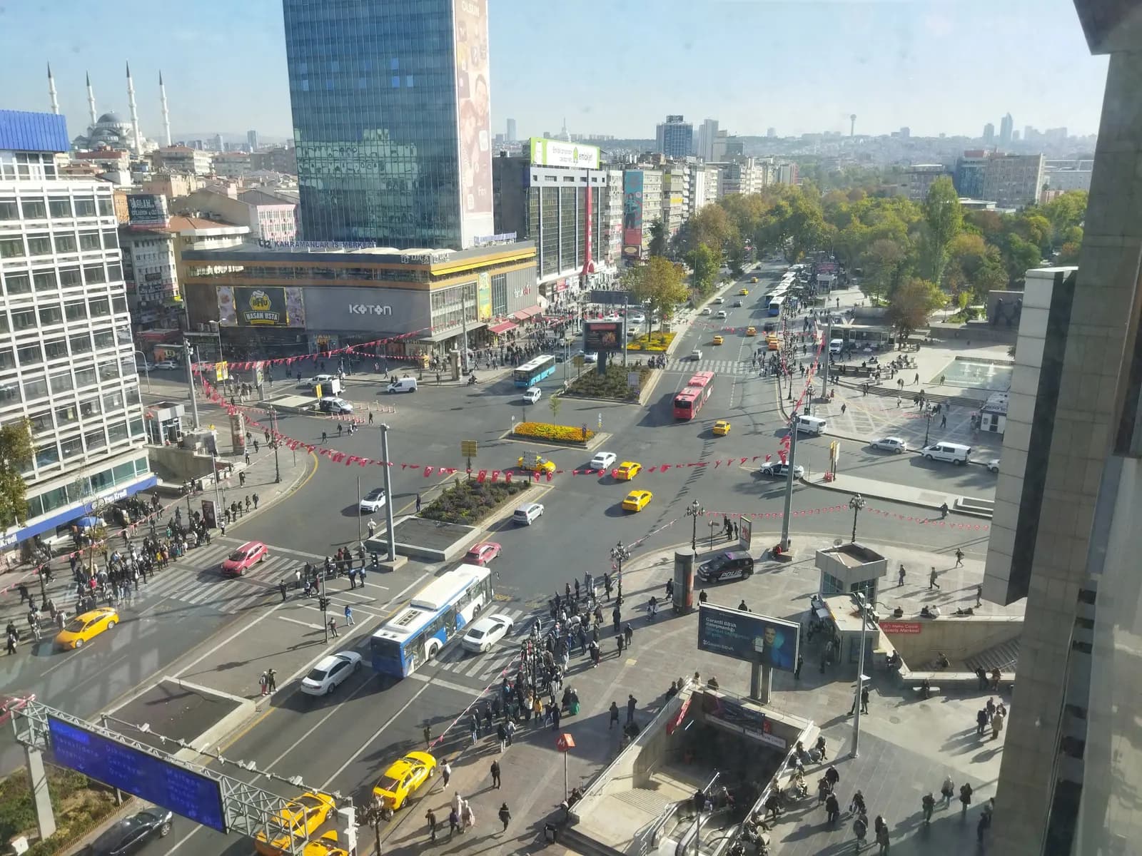Kızılay Square in Ankara seen from above, with buses, yellow taxis and crowds on the crossings between office towers