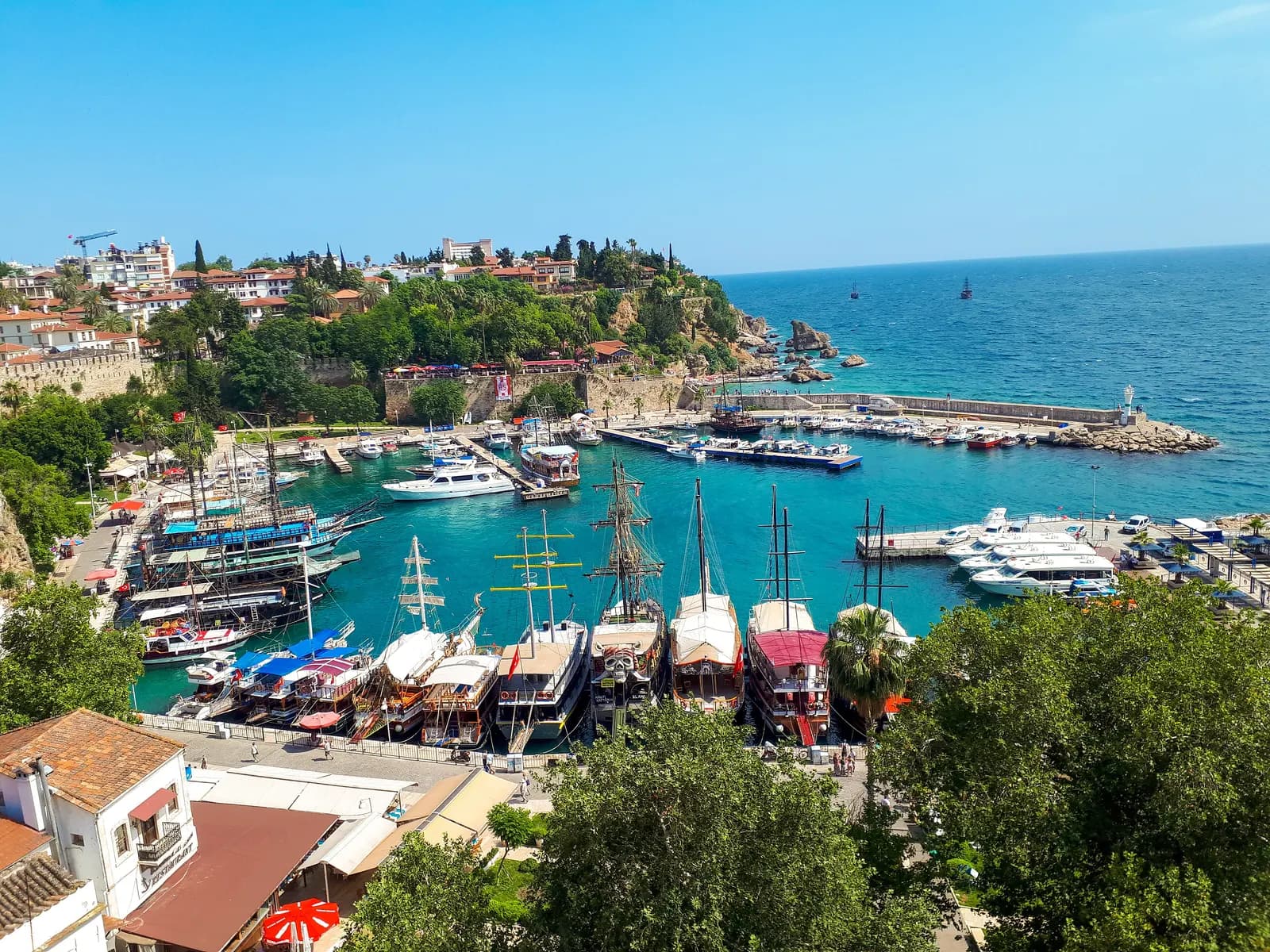 The old harbour of Kaleiçi seen from above, with wooden excursion boats and yachts moored below the old town walls and the cliffs