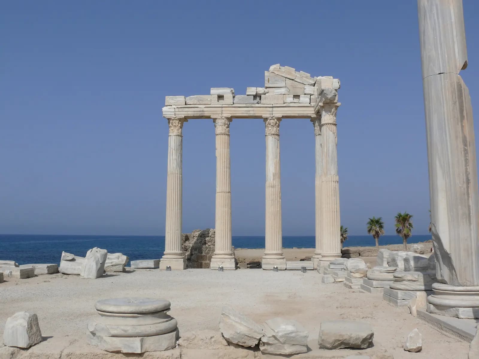 The standing marble columns of the Temple of Apollo at Side, with fallen blocks in front and the sea behind