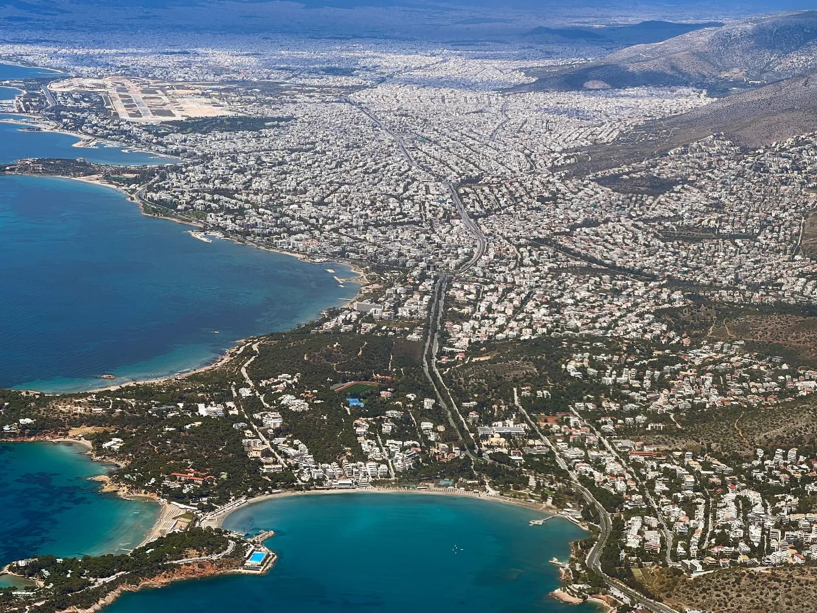 Aerial view of the bay and beach of Vouliagmeni, with the built up coast running north past Voula and Glyfada towards the former Hellinikon airport