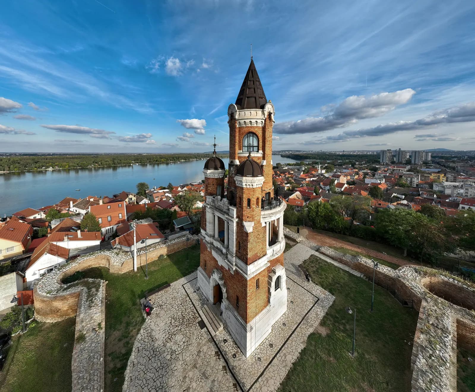 The brick Gardoš Tower in Zemun seen from above, with the old fortress walls around it, red-roofed houses and the Danube behind