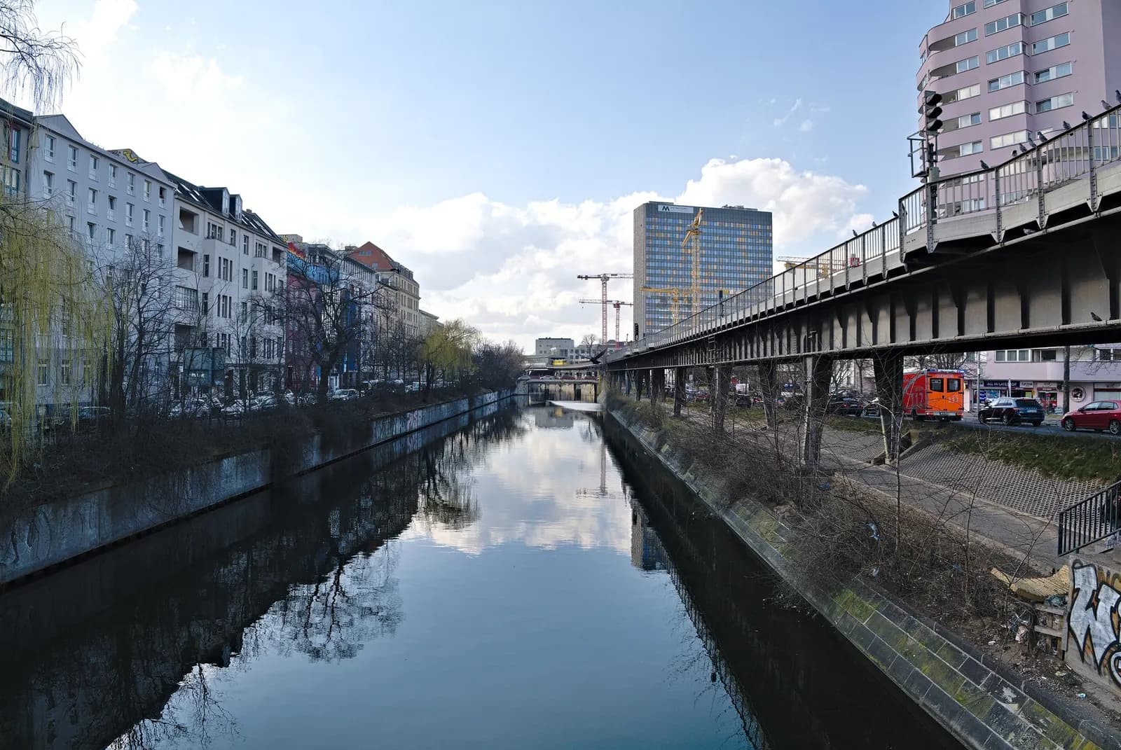 The Landwehr Canal in Kreuzberg looking west from Mehringbrücke, with apartment buildings on the left and the elevated U-Bahn line on the right