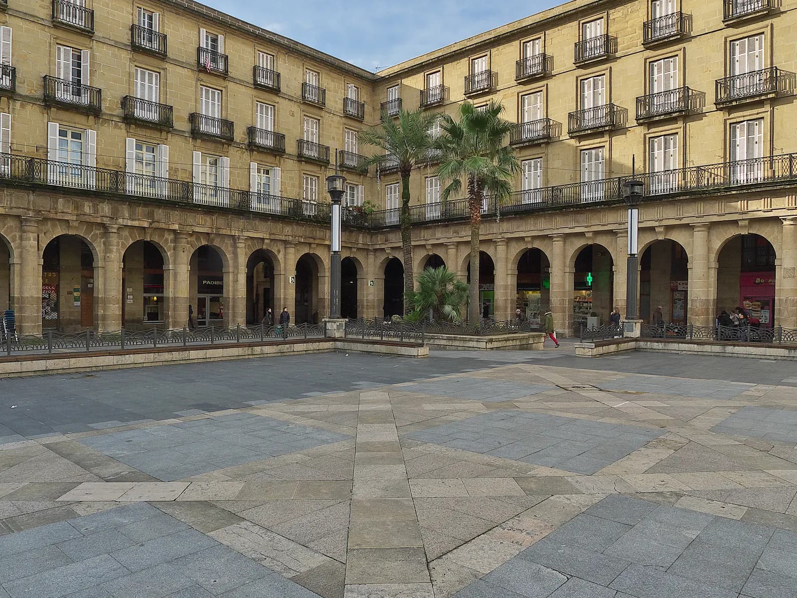 Plaza Nueva in Bilbao's Casco Viejo, an arcaded square with palm trees and a wide stone-paved centre.