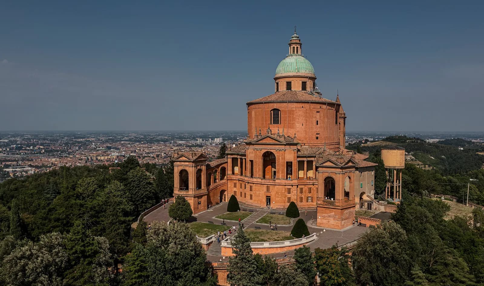 The brick Sanctuary of the Madonna di San Luca on its wooded hill above Bologna, with the city and the Po plain spread out behind it.
