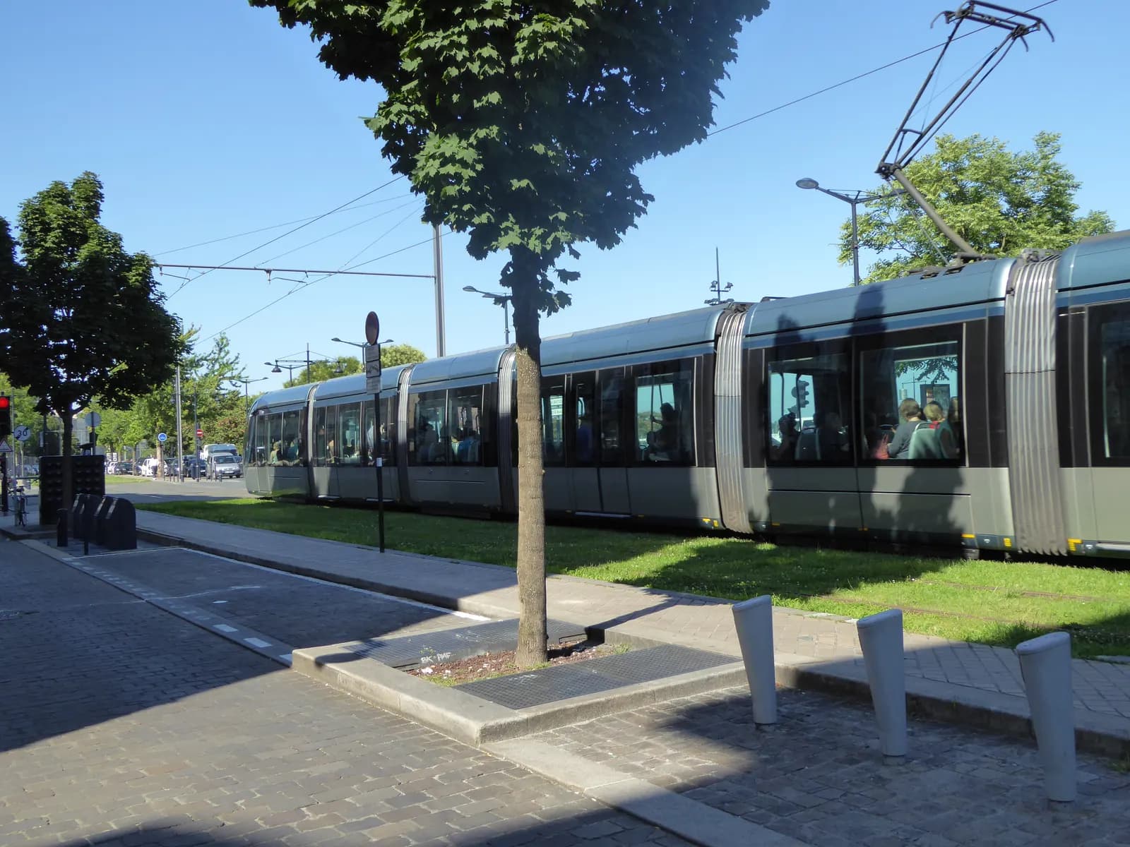A Bordeaux tram running on the grassed tracks along the quai des Chartrons, with a cycle lane and parked cars on the far side