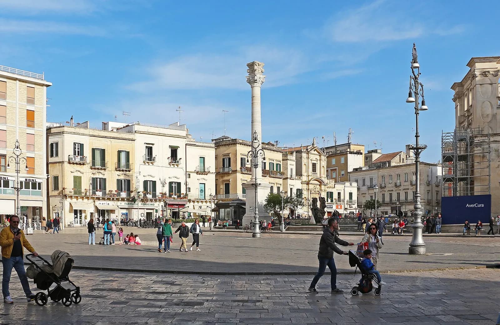 Piazza Sant'Oronzo in Lecce, with the column of Sant'Oronzo, pale stone buildings and people walking across the square