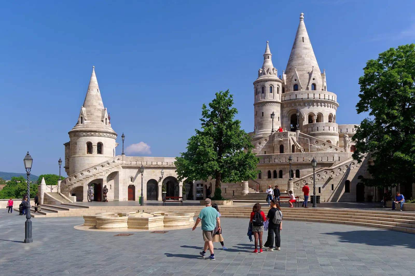 The white towers and stairways of the Fisherman's Bastion in the Buda Castle District, with visitors crossing the square in front