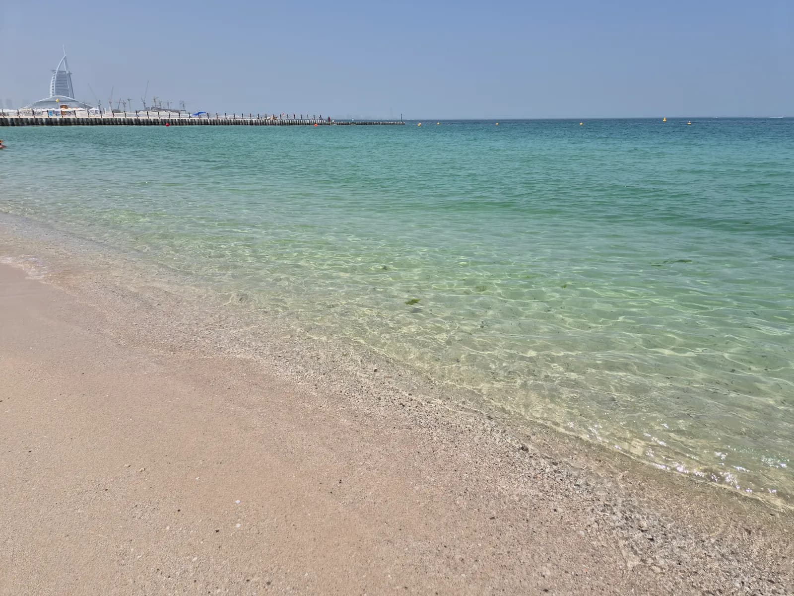 Clear shallow water at Kite Beach in Jumeirah, with the sail-shaped Burj Al Arab hotel on the horizon