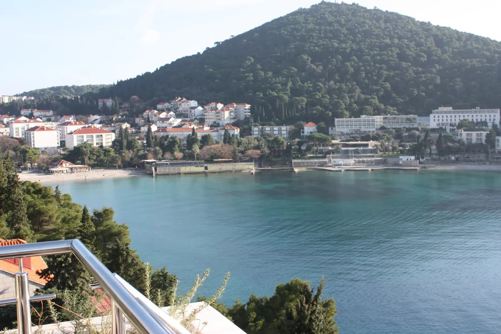 Lapad bay in Dubrovnik with its beaches, hotels and apartment buildings below a wooded hill, seen from a terrace in winter
