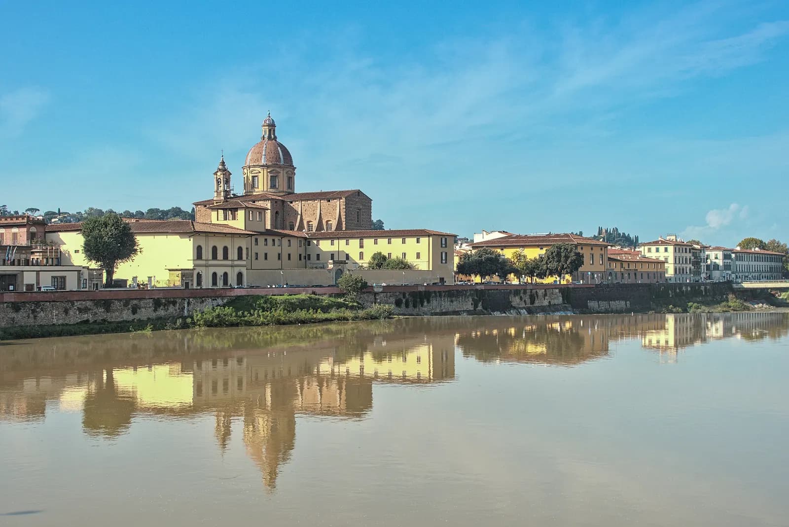 The dome of San Frediano in Cestello and the Oltrarno riverfront reflected in the Arno, seen from the Ponte alla Carraia.