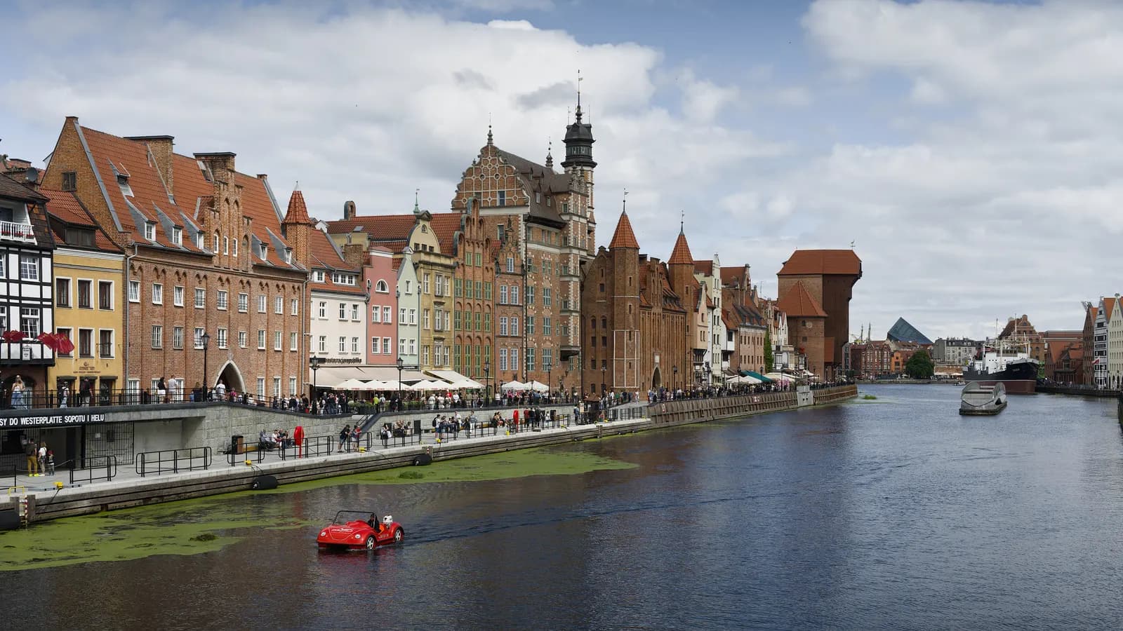 The Motława river in Gdańsk with the gabled houses of Długie Pobrzeże along the quay and the brick and timber Crane gate further down the bank