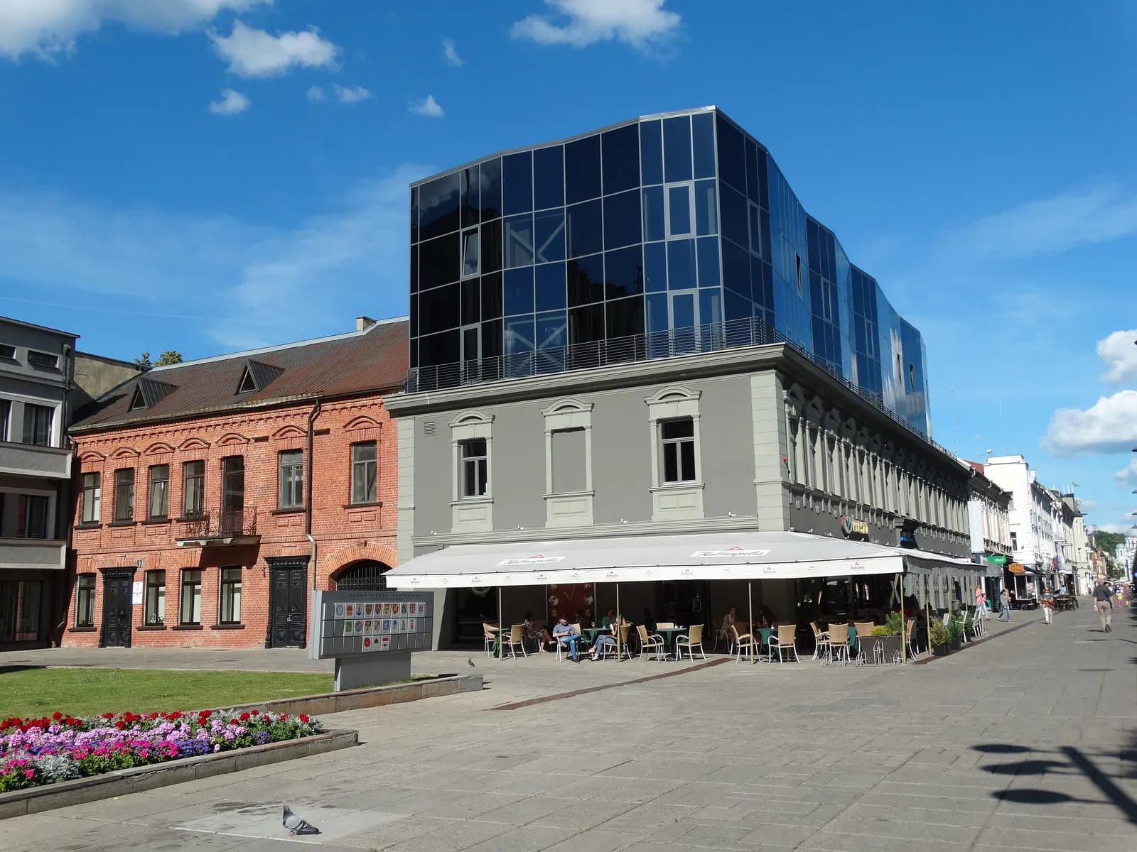 A building with a glass upper storey above café tables on Laisvės alėja, the pedestrian avenue in central Kaunas