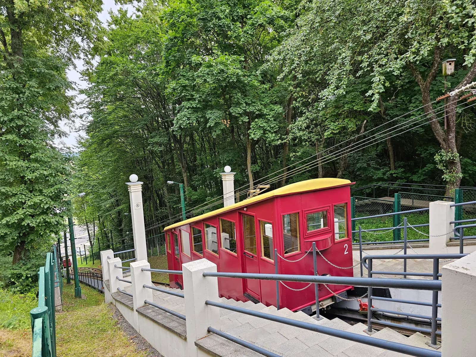 The red car of the Žaliakalnis funicular on its track among trees in Kaunas