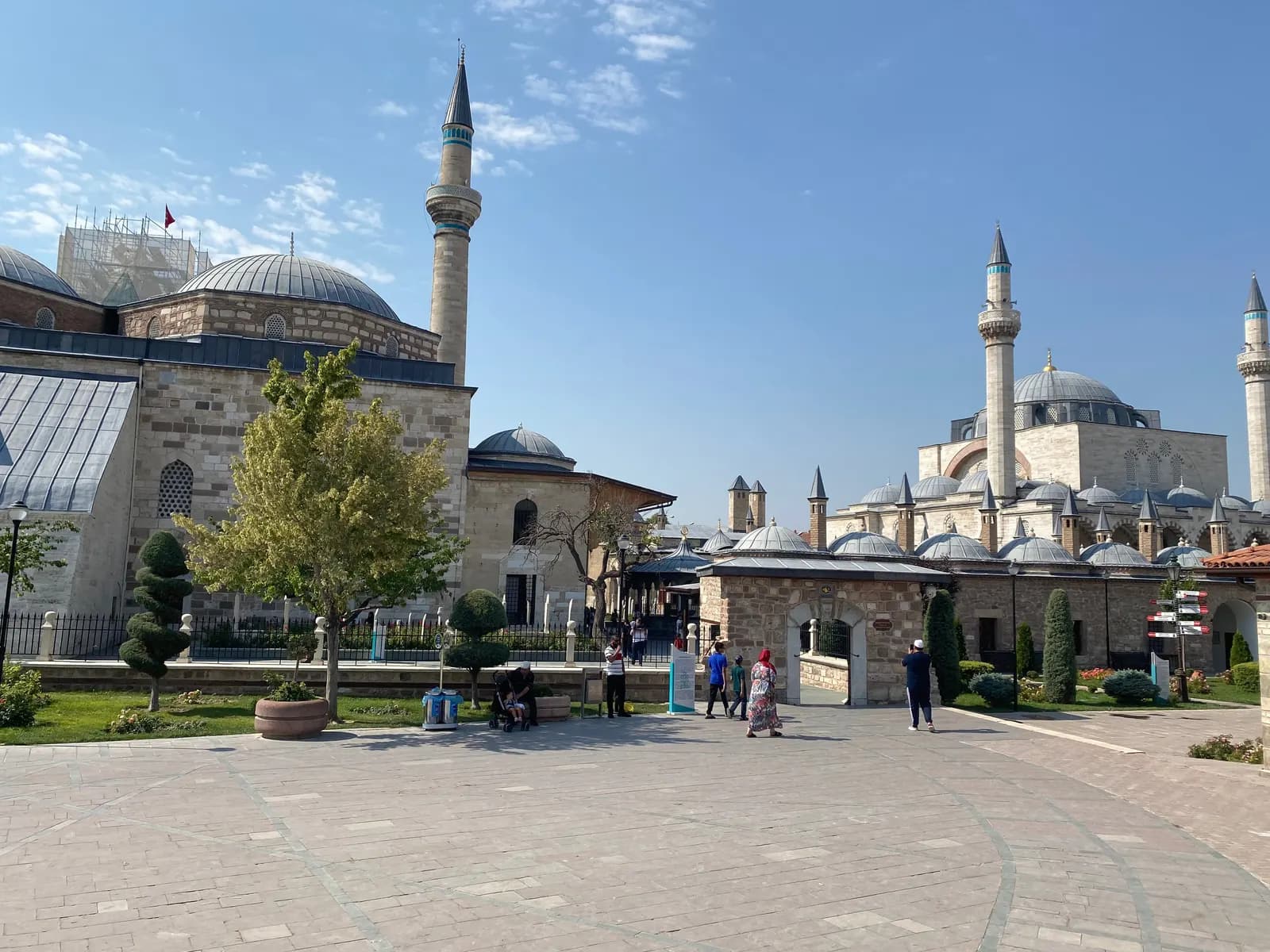 The paved square at the Mevlana Museum, with the museum domes and a minaret on the left and a large mosque with two minarets on the right