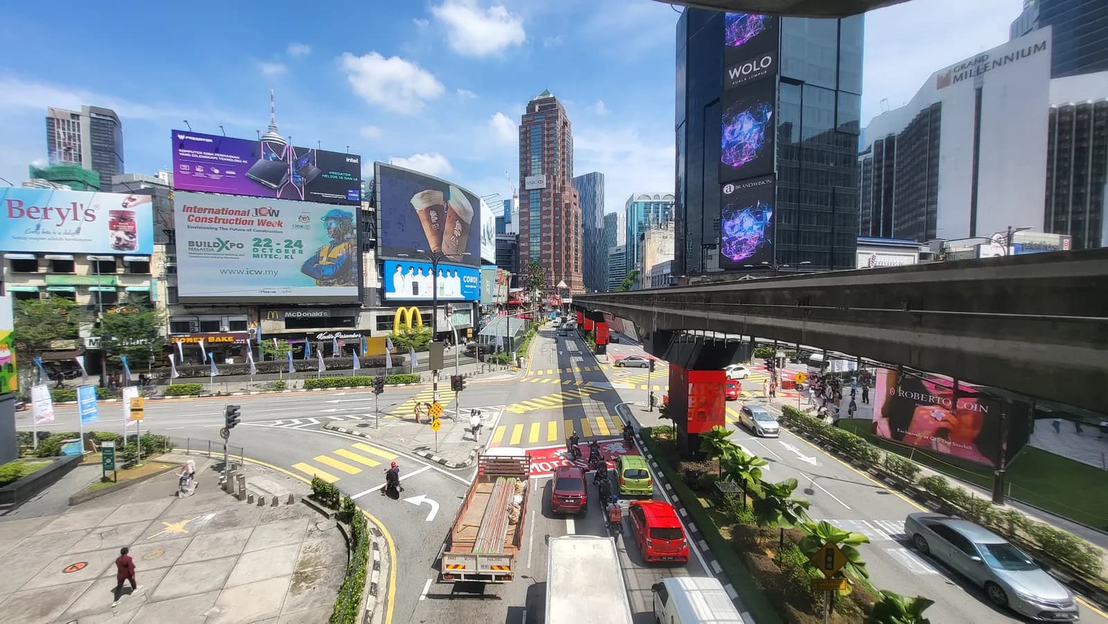 The Bukit Bintang junction in Kuala Lumpur, with cars and motorcycles on Jalan Sultan Ismail, the monorail track overhead and billboards on the shopping buildings