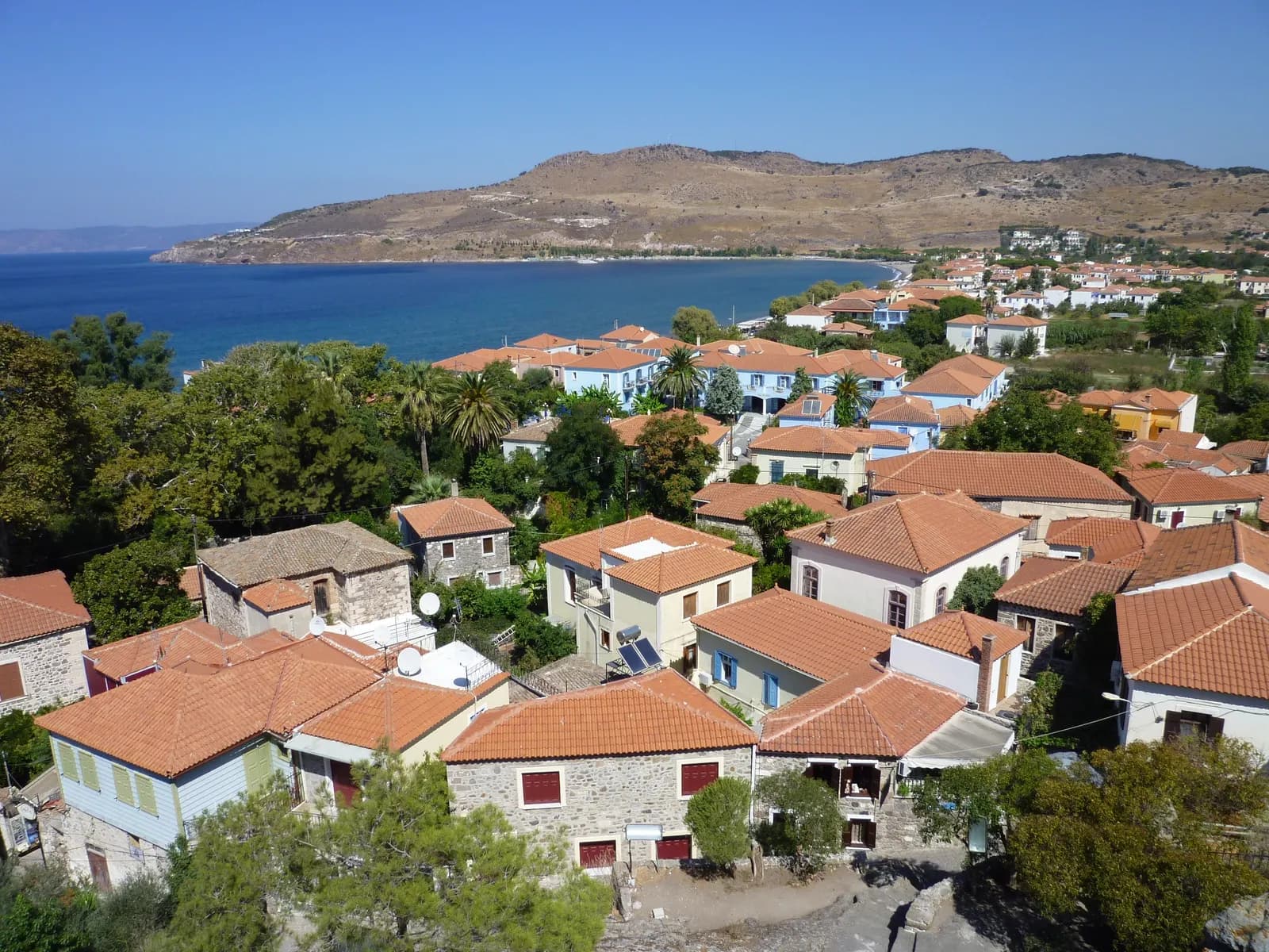 Tiled rooftops of Petra with the bay and its beach curving towards a bare headland