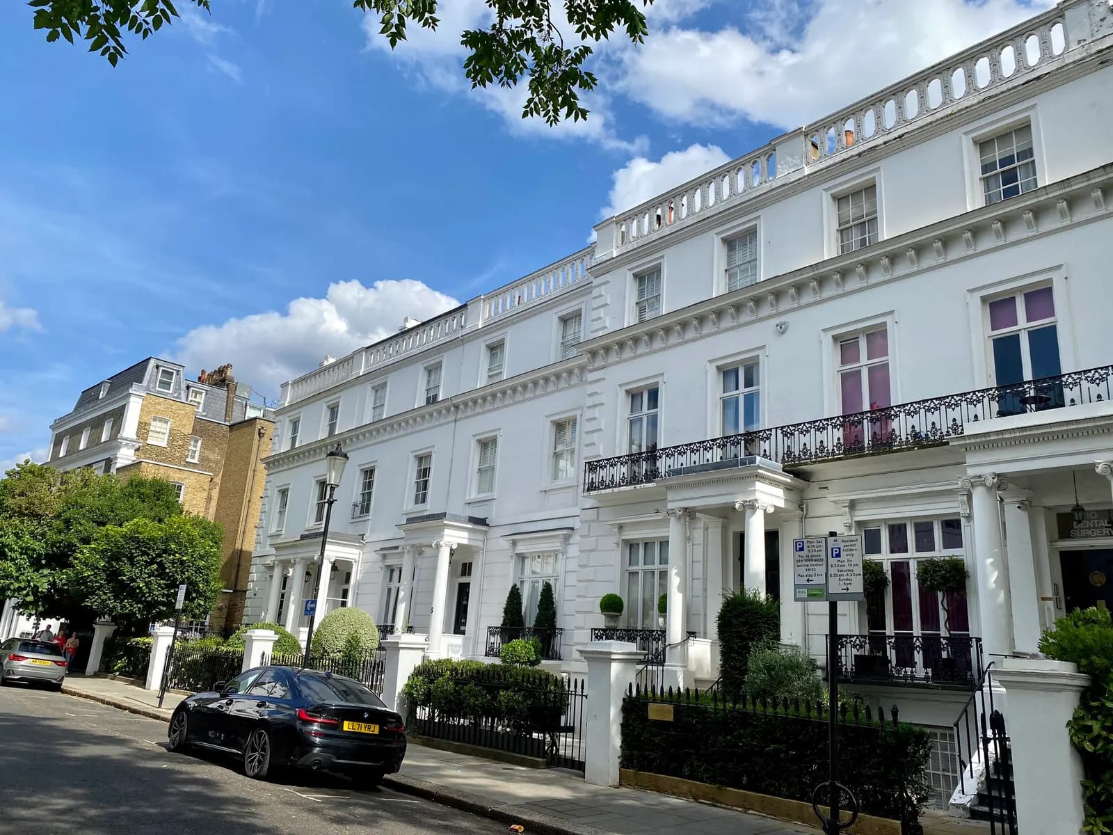 White stucco terraced houses on Thurloe Street in South Kensington, with parking signs and a car parked at the kerb