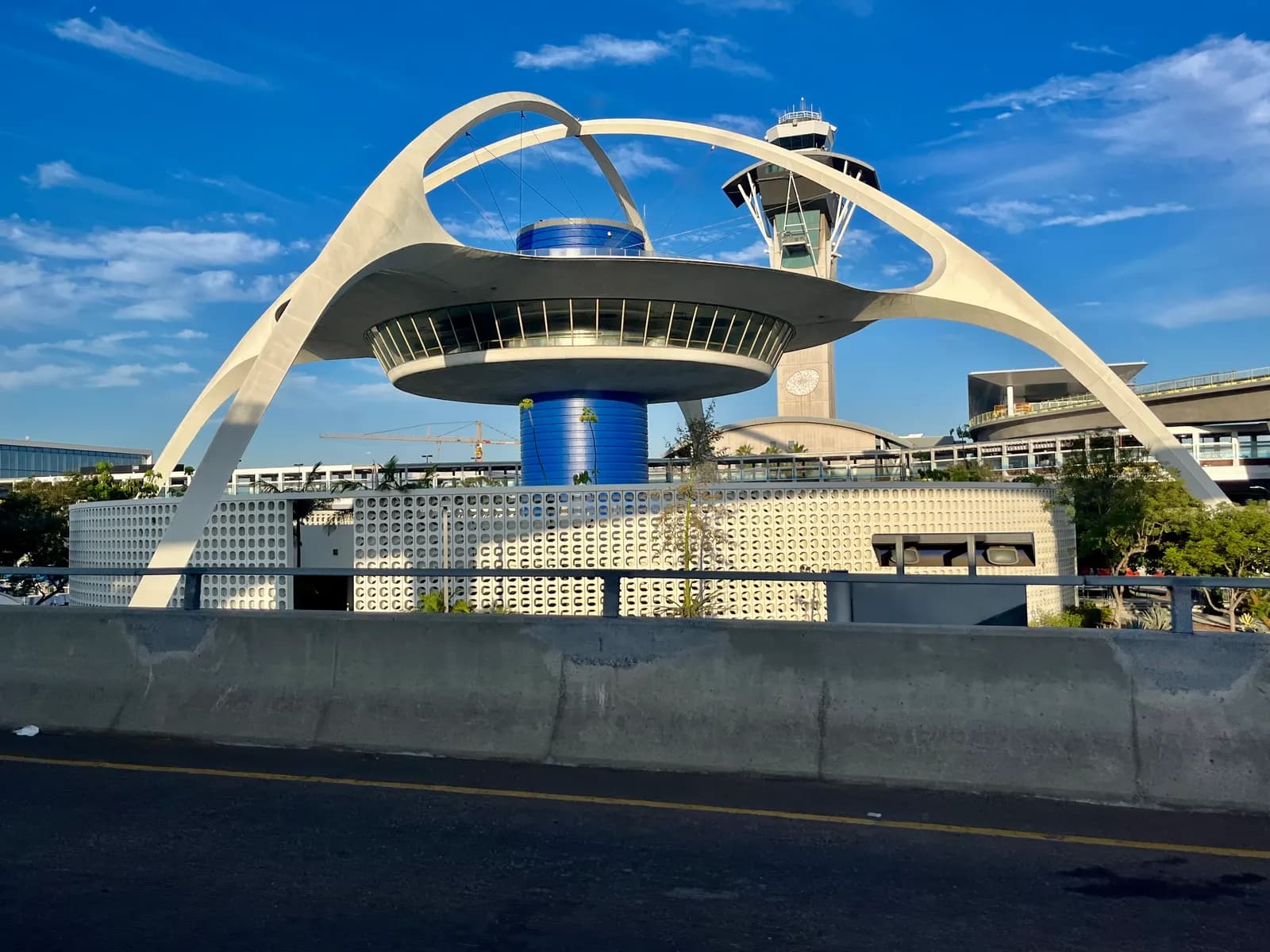 The arched Theme Building at Los Angeles International Airport with the control tower behind it, seen from the terminal road