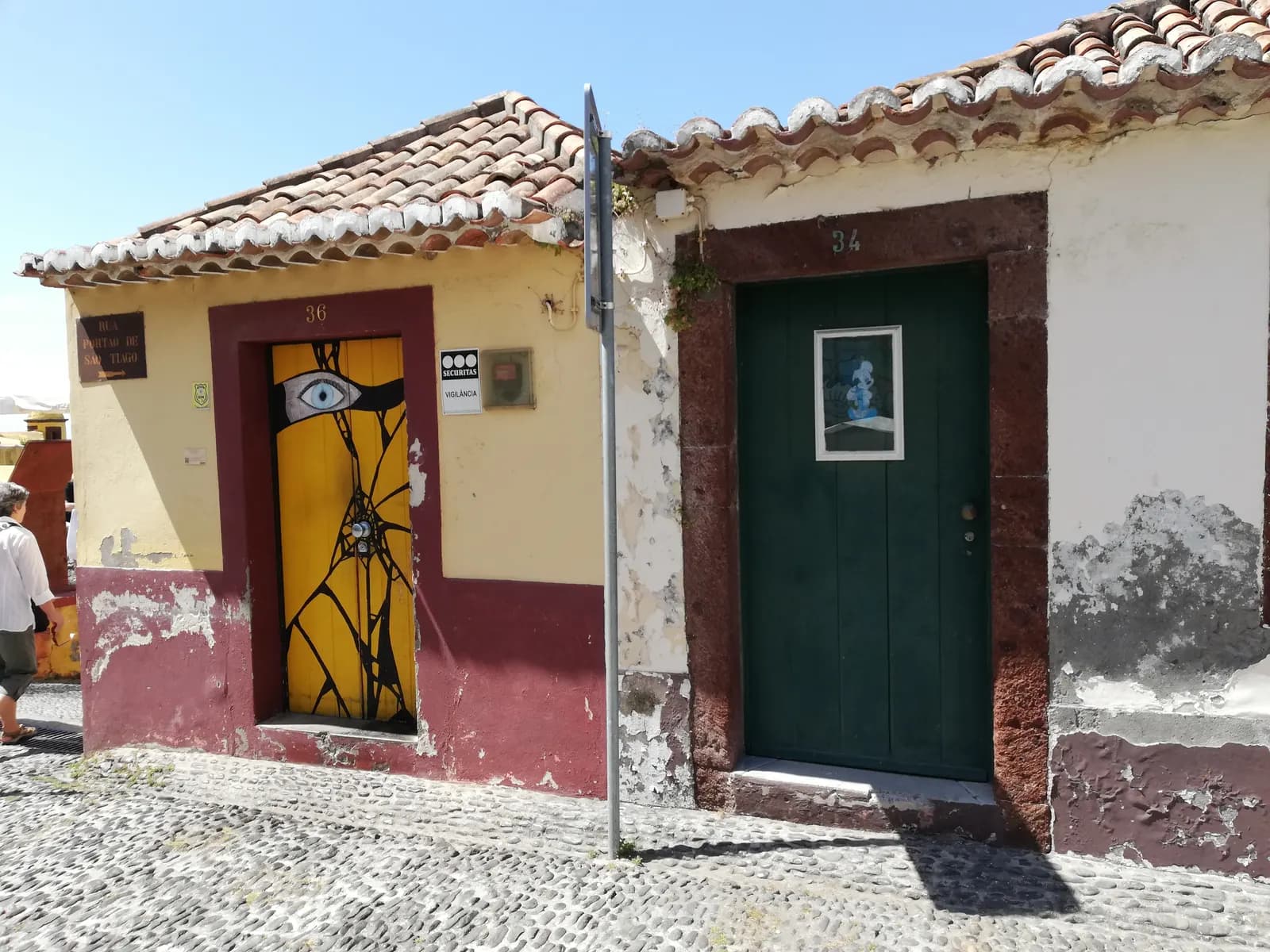 Two small old houses with tiled roofs and painted front doors on a cobbled street in the Zona Velha, Funchal's old quarter
