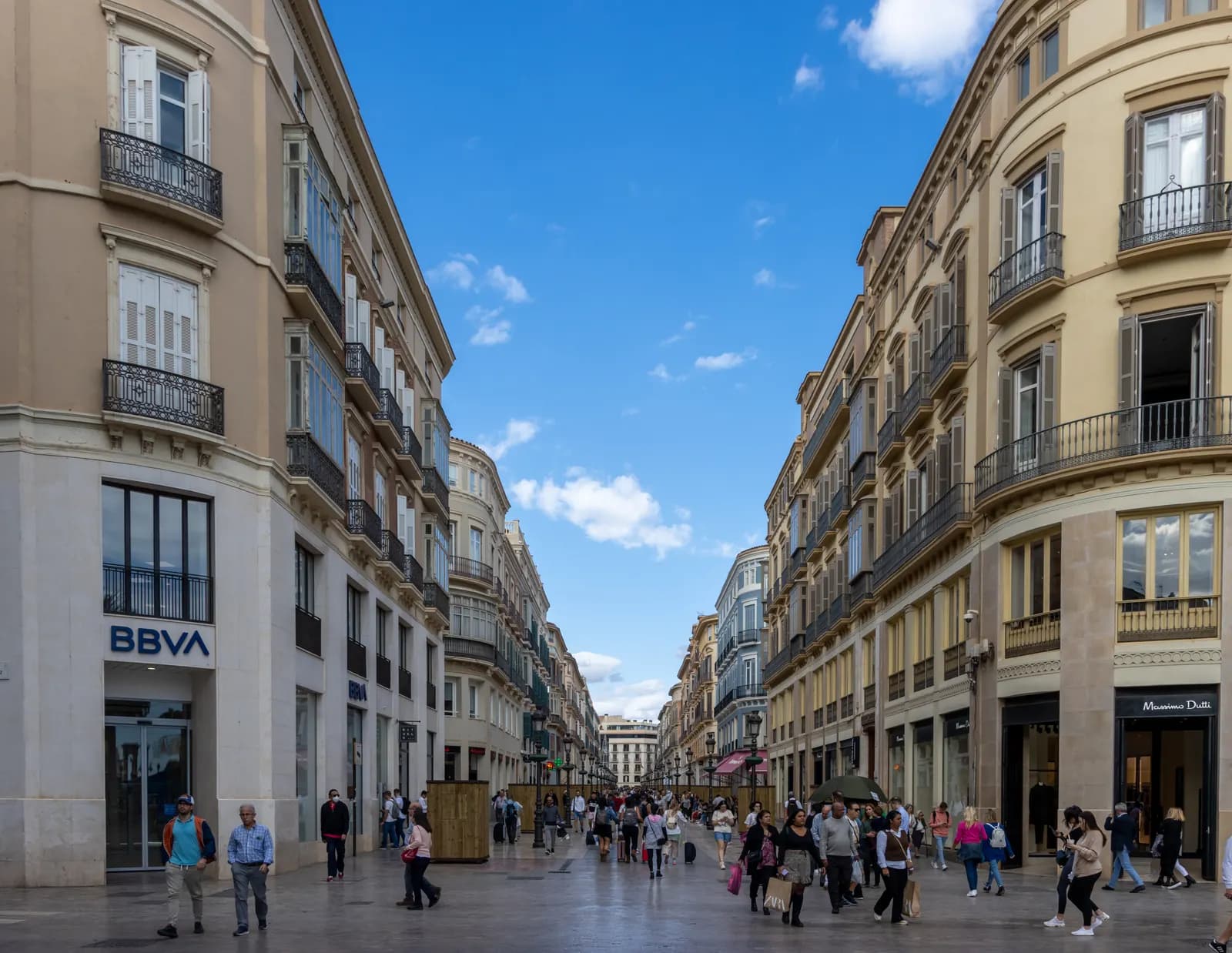 Shoppers on the marble-paved Calle Larios between cream-coloured nineteenth-century buildings.