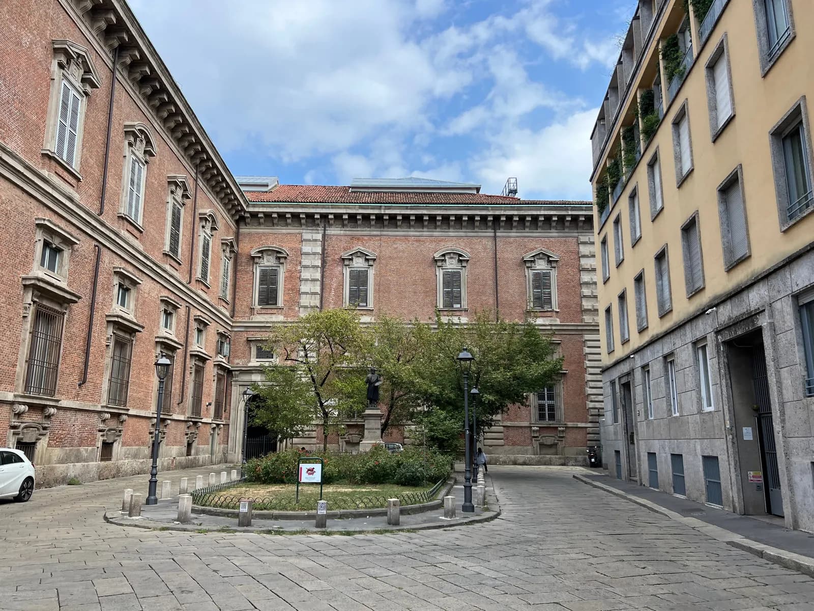 The brick Palazzo di Brera around a small garden with a statue of the painter Francesco Hayez, on a paved street in Brera.