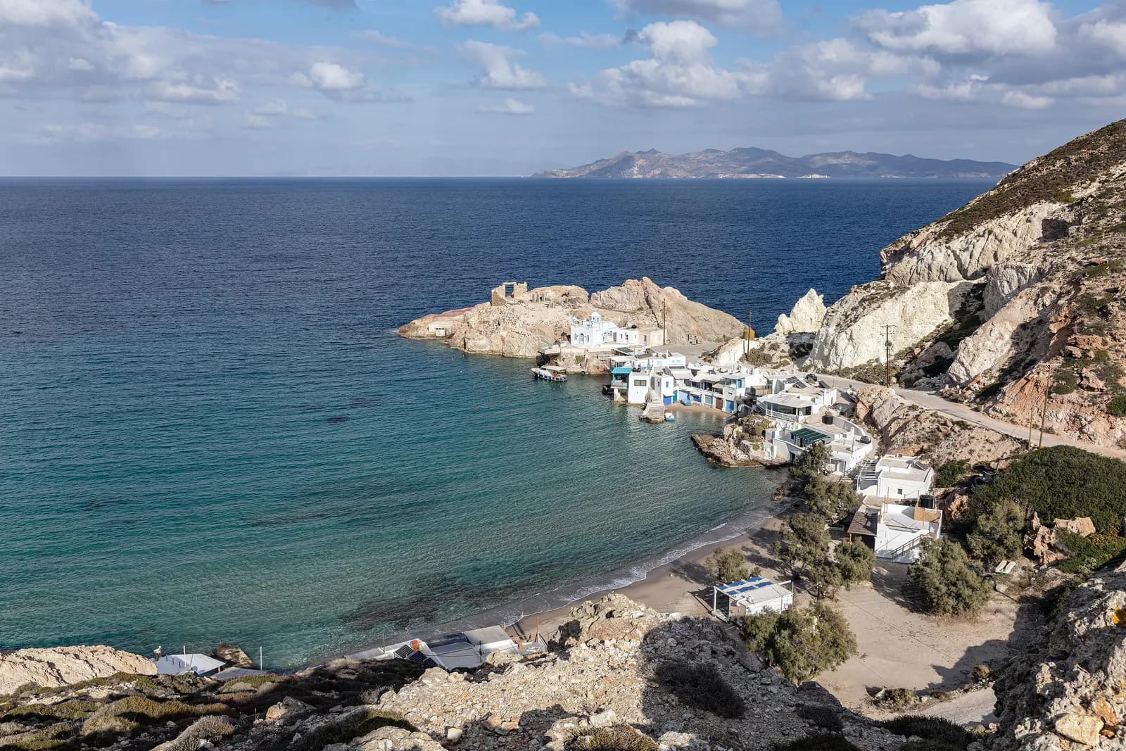 The cove of Firopotamos with fishermen's houses and a white chapel on the rocks above a small beach
