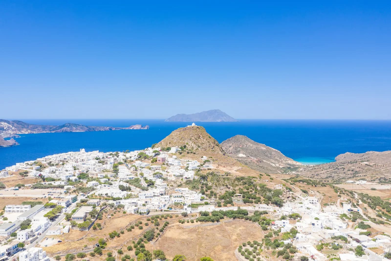 Aerial view over Plaka towards the castle hill, with the sea, the bay and an island on the horizon