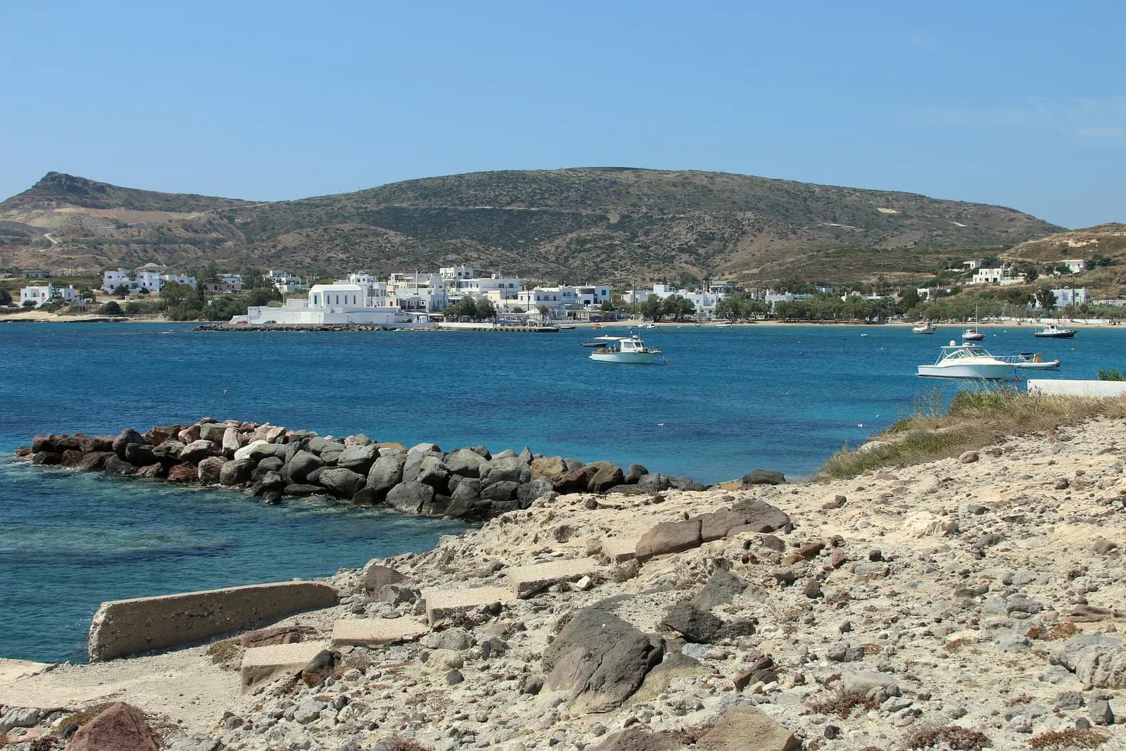 Pollonia across its bay, with white houses along the shore, moored boats and a low hill behind