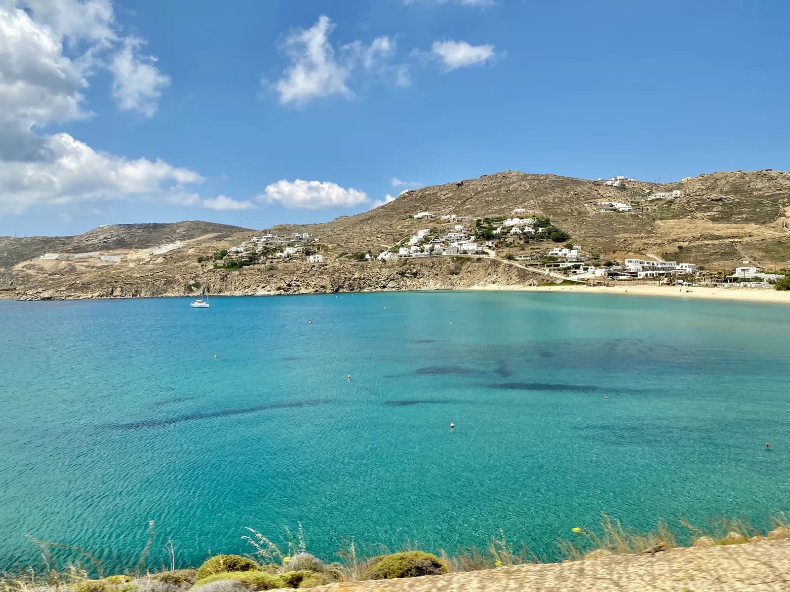 The long turquoise bay of Kalo Livadi on the south coast, with a sandy beach and white houses on the hills behind
