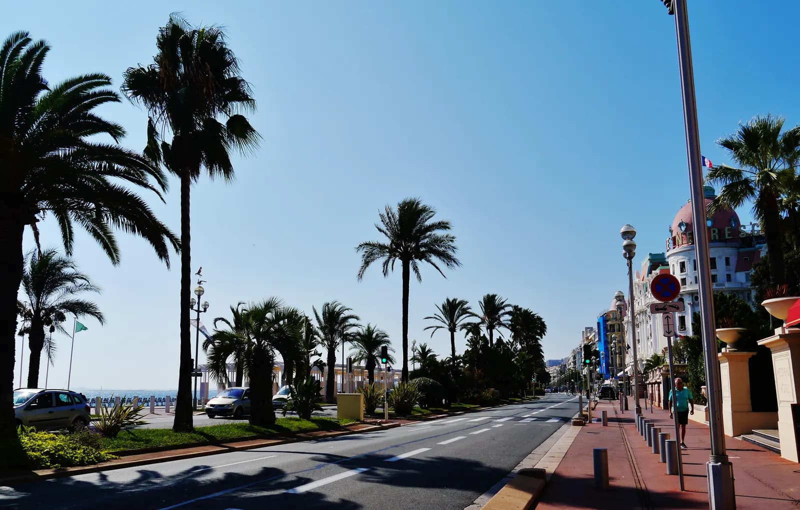 The Promenade des Anglais in Nice, with palm trees along the seafront, the sea on the left and the dome of a grand hotel on the right