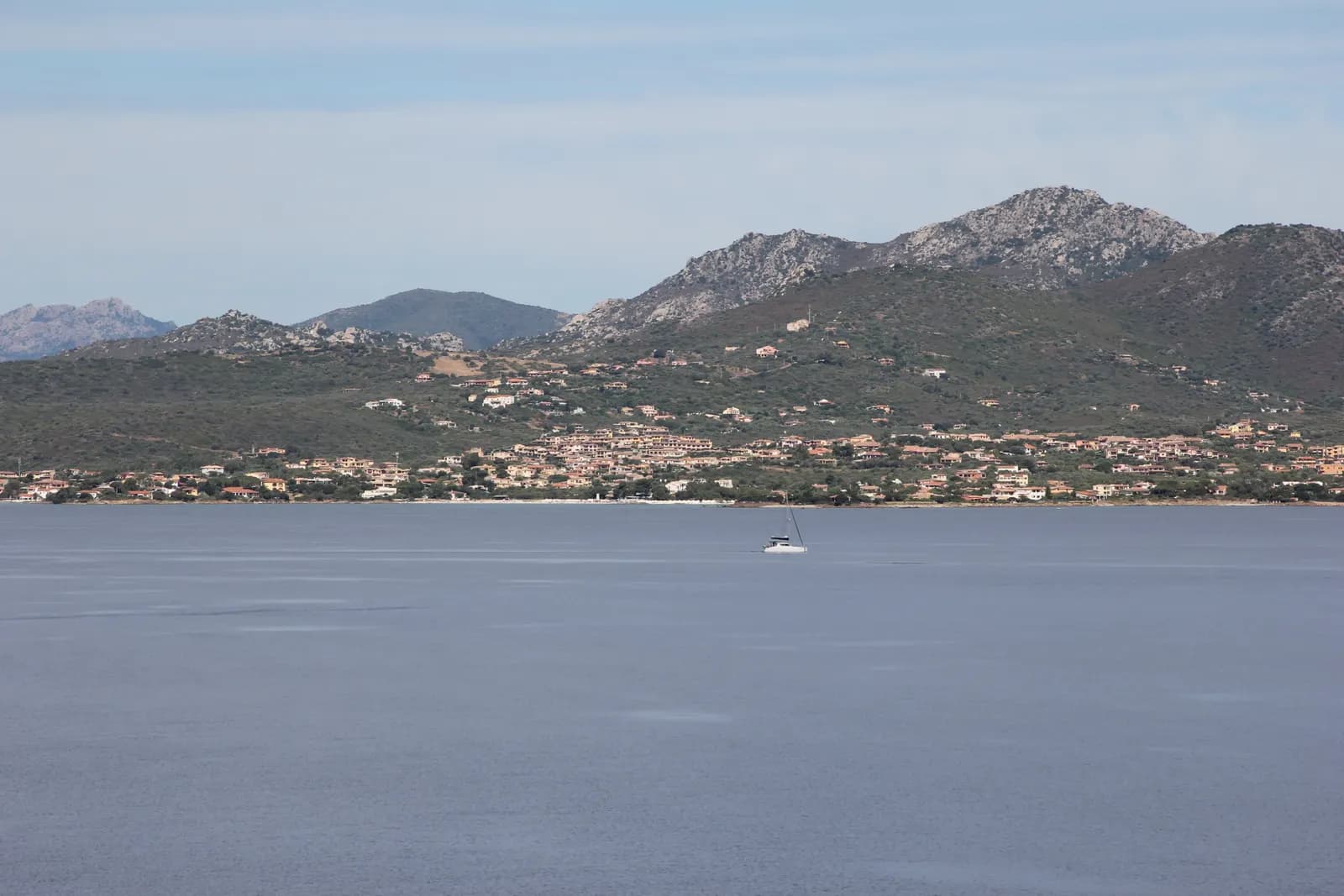 The Pittulongu shore north east of Olbia seen from the water, houses scattered along the coast under bare granite hills