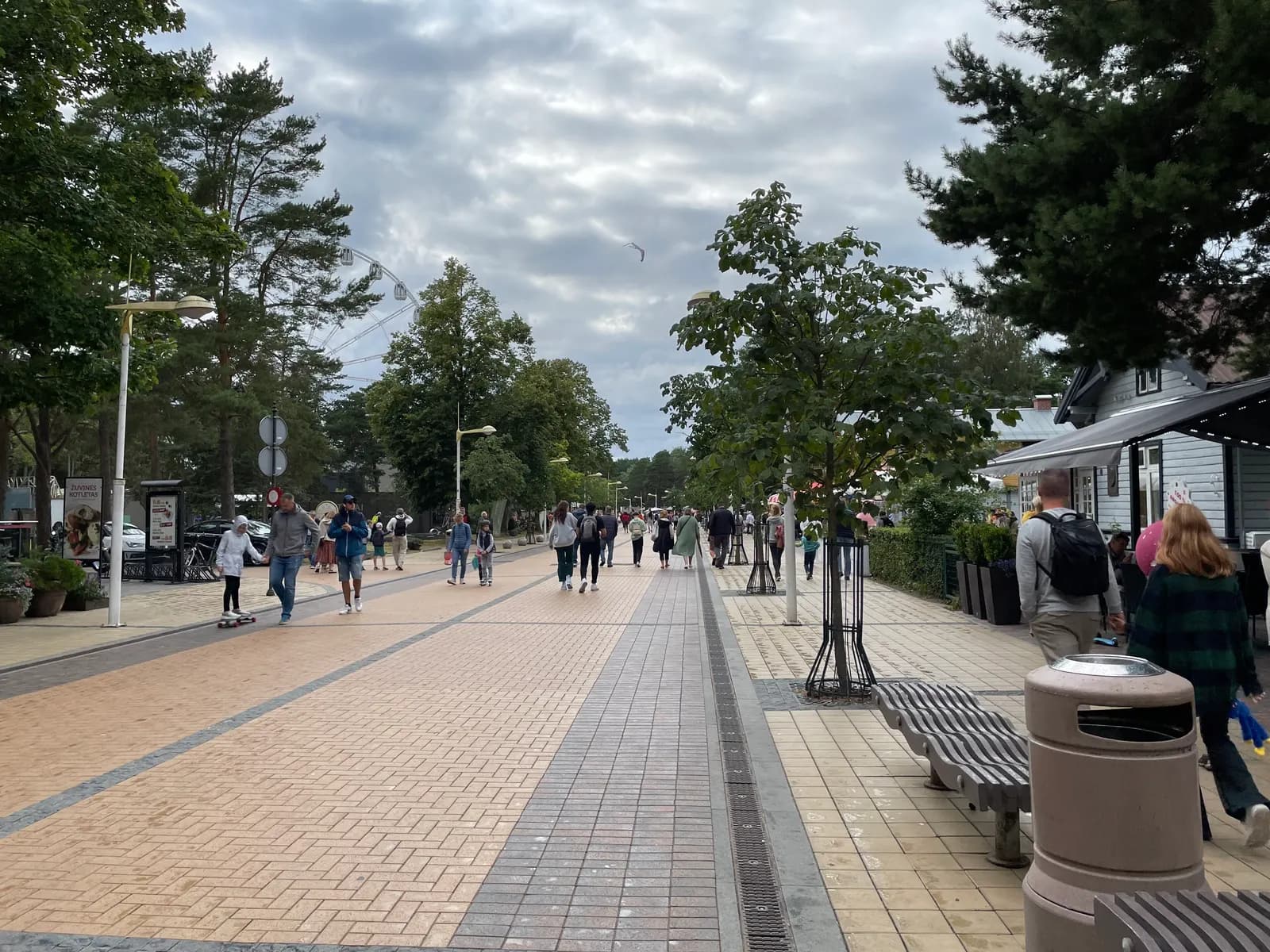 J. Basanavičiaus street in Palanga, a wide pedestrian street with trees and benches and a Ferris wheel behind