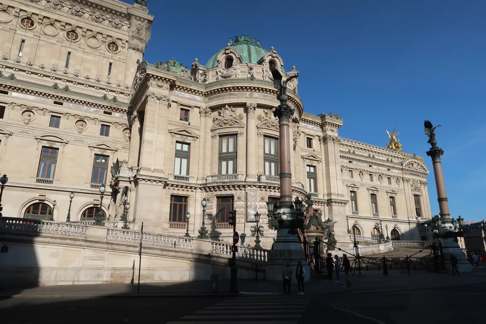 The side facade of the Palais Garnier opera house in the 9th arrondissement, with its green dome, gilded figures and lamp columns