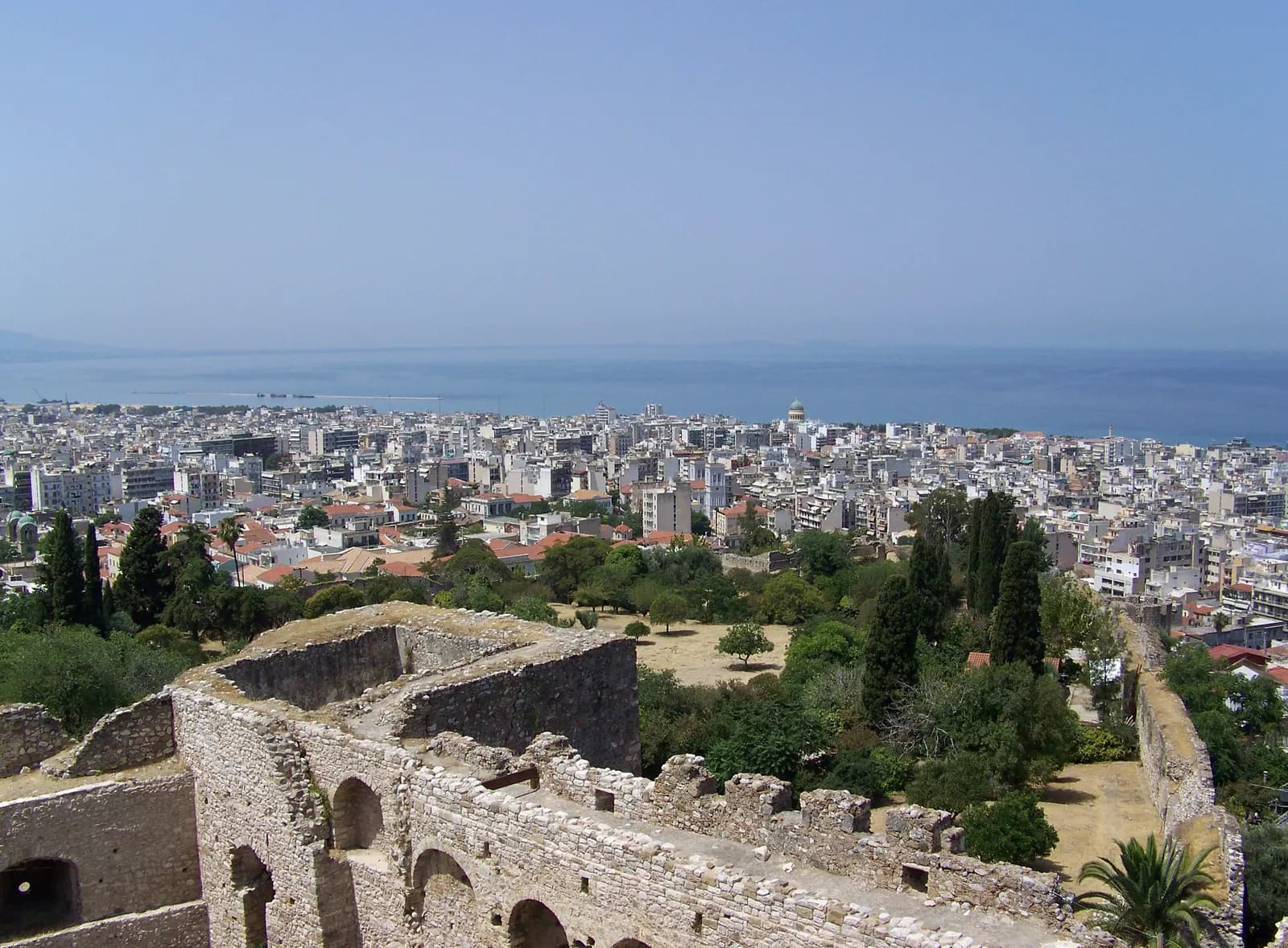 Central Patras seen from the castle walls, a dense spread of white apartment blocks running down to the port and the Gulf of Patras