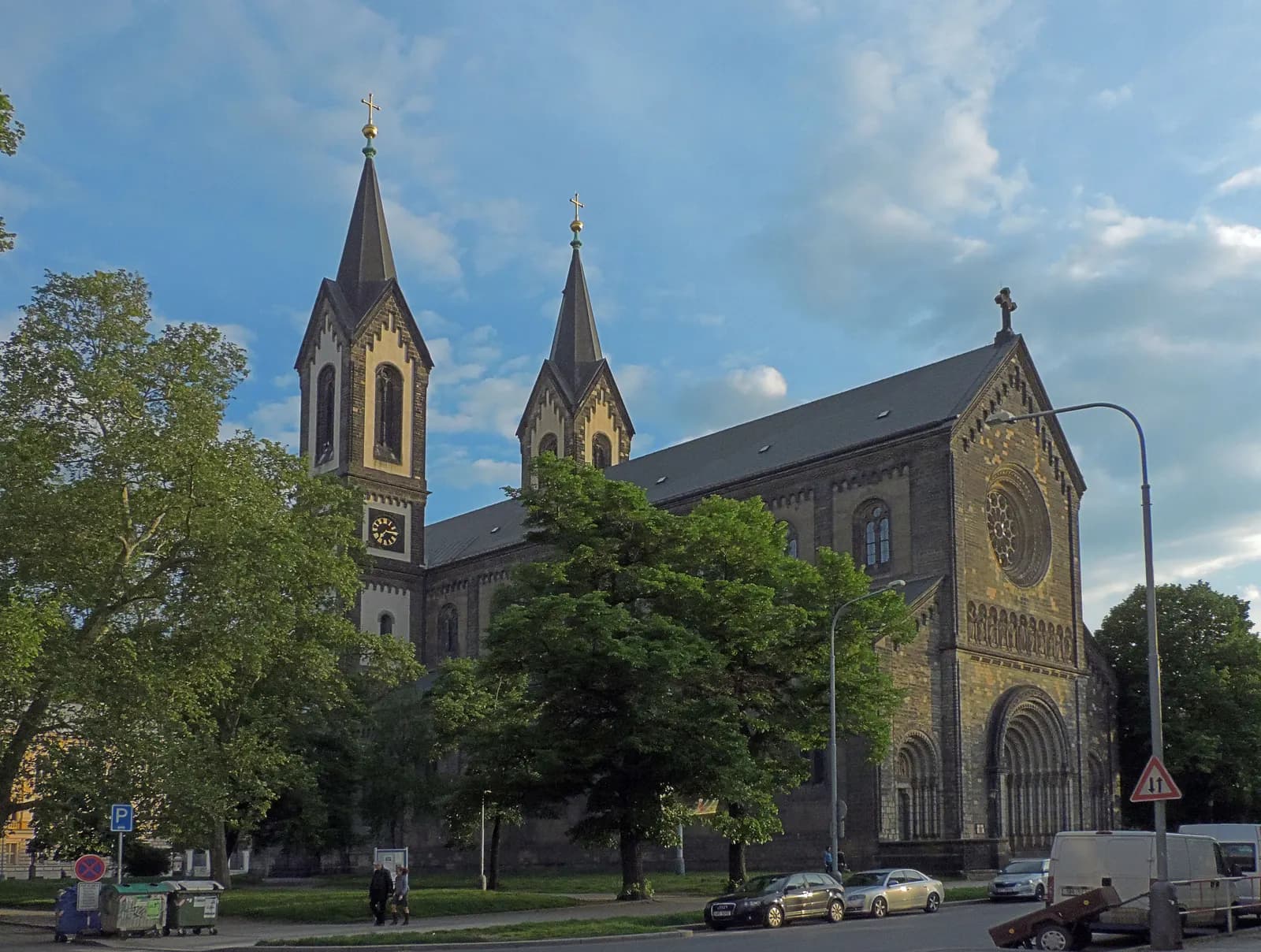 The twin-towered Church of Saints Cyril and Methodius on Karlínské náměstí in Karlín, with trees and cars parked along the street